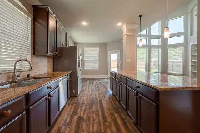 a kitchen with granite countertop a sink stove and cabinets