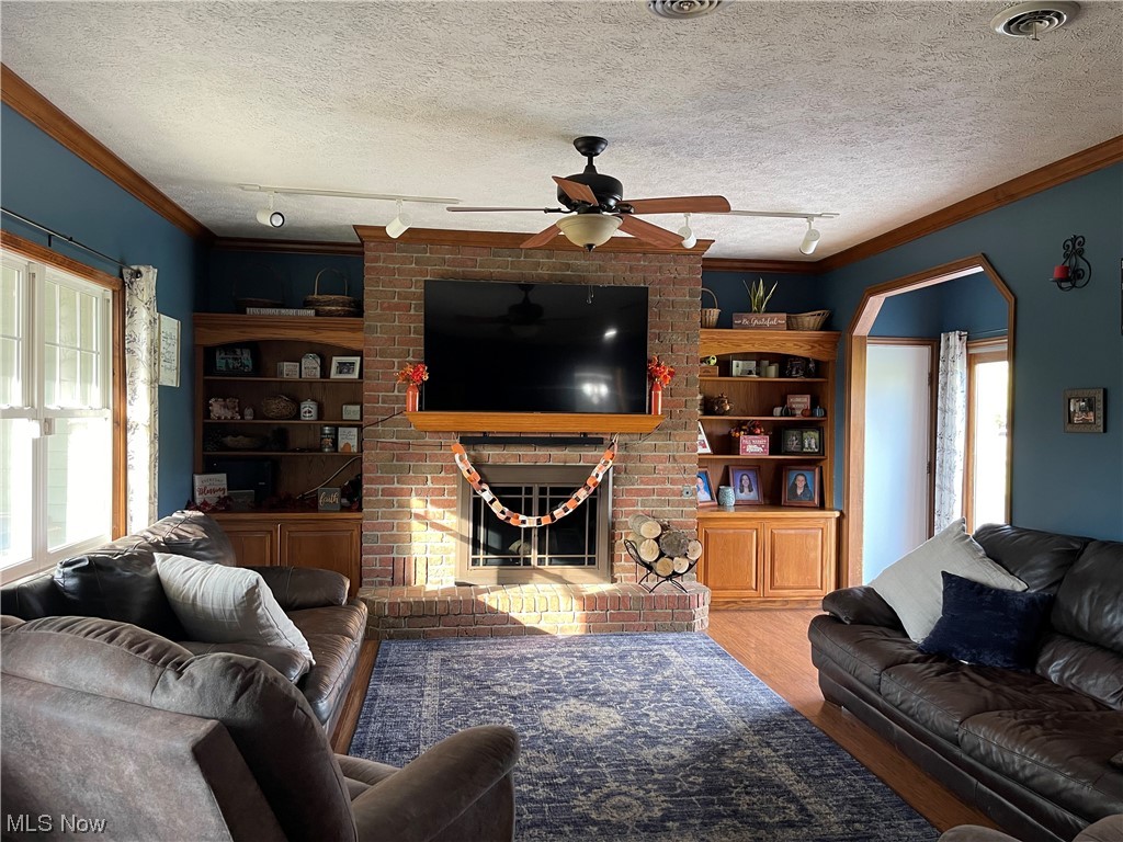 9104 Cherry Road Vermilion, OH 44089 - Photo 3 of 27 Living room with dark vinyl-laminate flooring, rail lighting, ceiling fan, a textured ceiling, and a wood burning fireplace.