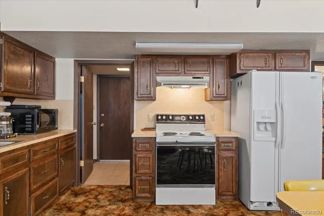 a kitchen with stainless steel appliances granite countertop a refrigerator a stove and a sink