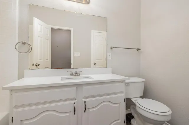 a bathroom with a toilet sink vanity and mirror