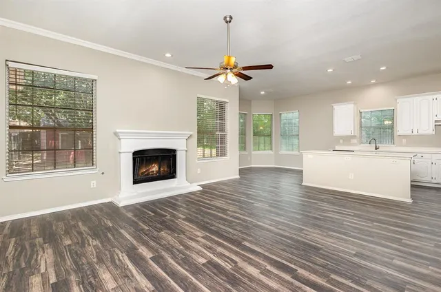 a view of a kitchen with a fireplace a ceiling fan and wooden floor