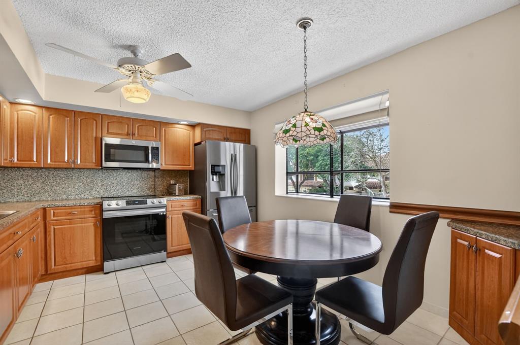 7873 La Mirada Drive, Unit 7873 Boca Raton, FL 33433 - Photo 5 of 40 a kitchen with stainless steel appliances granite countertop a stove a sink dishwasher a dining table and chairs with wooden floor
