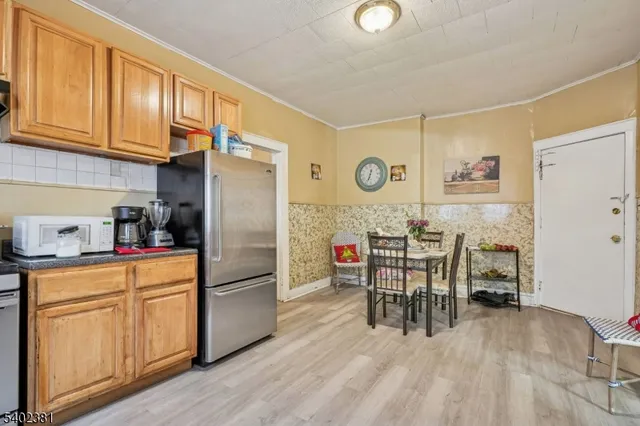 a kitchen with granite countertop a refrigerator a stove a dining table and chairs with wooden floor