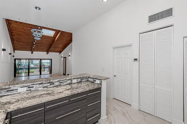 a view of kitchen with granite countertop cabinets and window