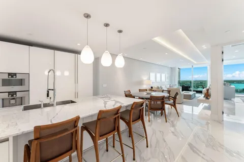 a kitchen with stainless steel appliances kitchen island granite countertop a sink a stove a dining table chairs and view living room