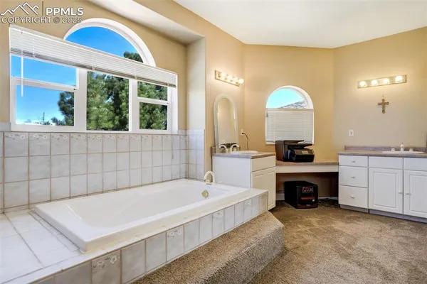 a bathroom with a tub a double vanity sink and a large window