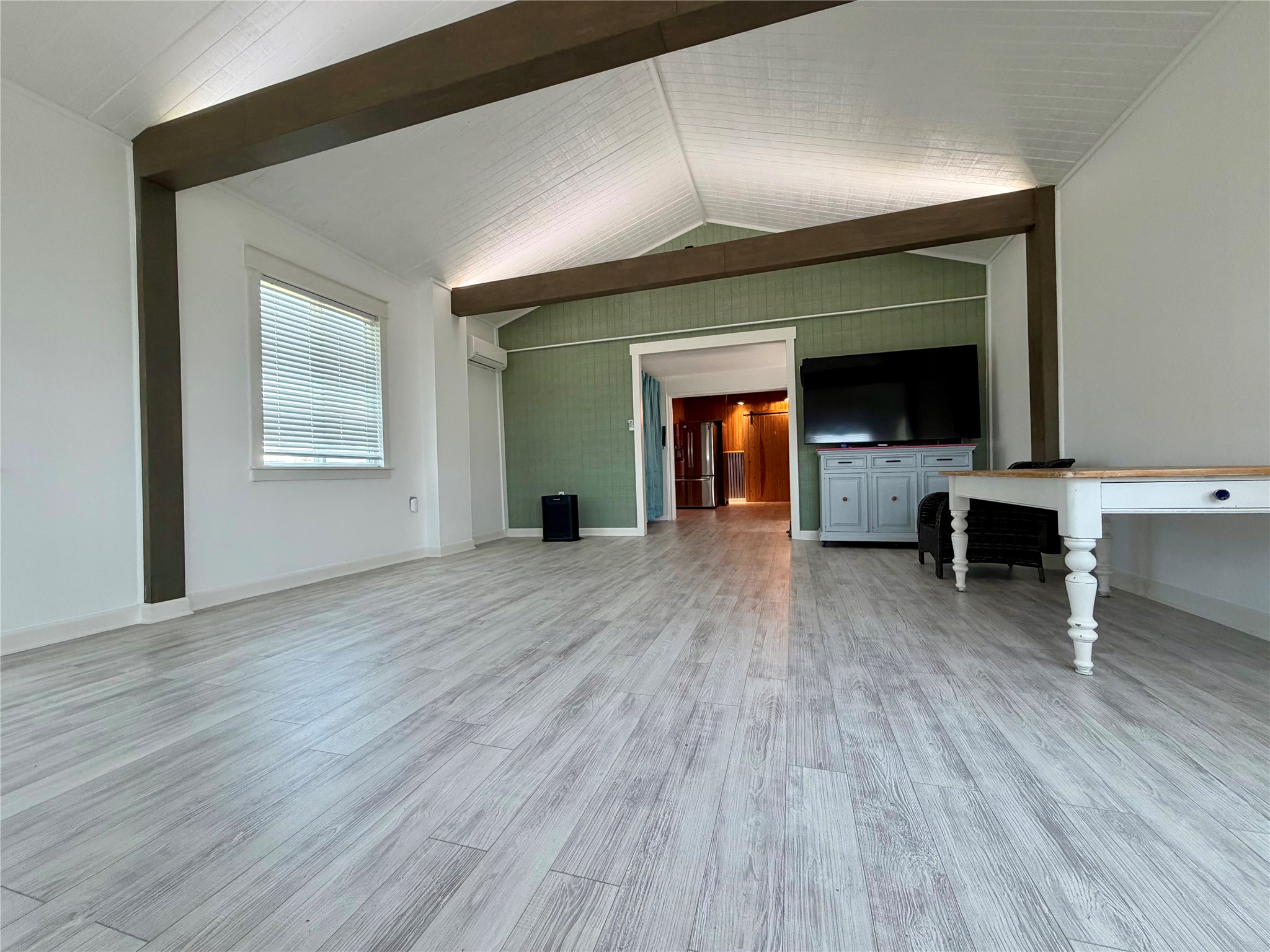 441 Molasses Road Dale, TX 78616 - Photo 18 of 36 A spacious room features vaulted ceilings, exposed beams, and light-toned wood flooring.