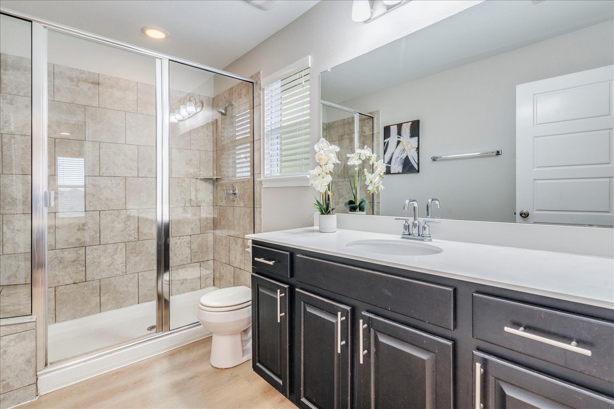 10317 Laurie Lane Austin, TX 78747 - Photo 15 of 35 Full bath featuring vanity, a shower stall, and light wood-style flooring