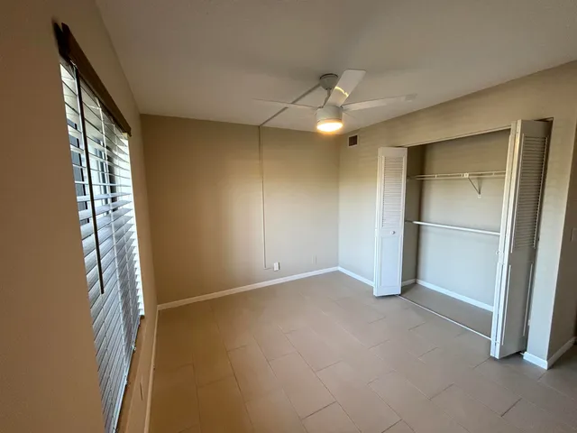 an empty room with closet and a chandelier fan