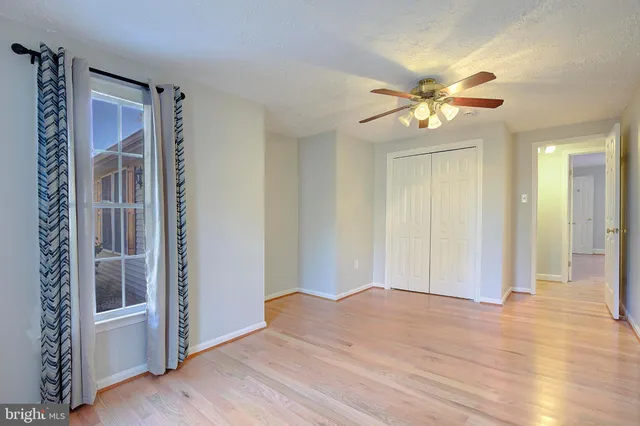 a view of empty room with wooden floor and fan