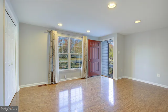 an empty room with wooden floor and windows
