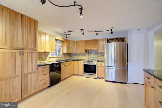 a kitchen with granite countertop a refrigerator stove and sink