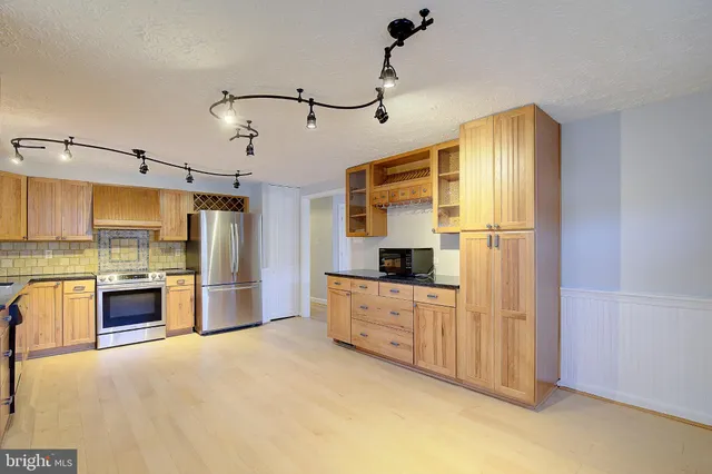 a kitchen with stainless steel appliances granite countertop a refrigerator a oven and white cabinets with wooden floors