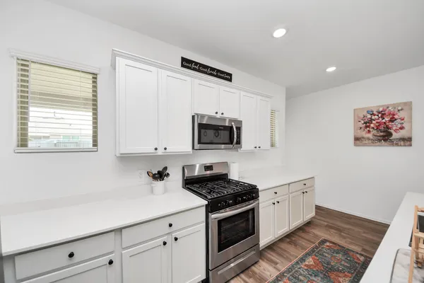 a kitchen with stainless steel appliances white cabinets and a stove top oven