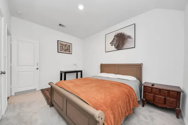 a bed room with a bed and a lamp on a dresser