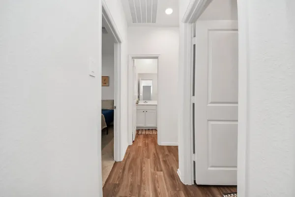 a view of a hallway with wooden floor and a bathroom