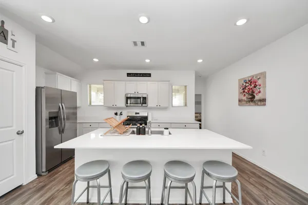 a kitchen with stainless steel appliances a dining table chairs refrigerator and sink