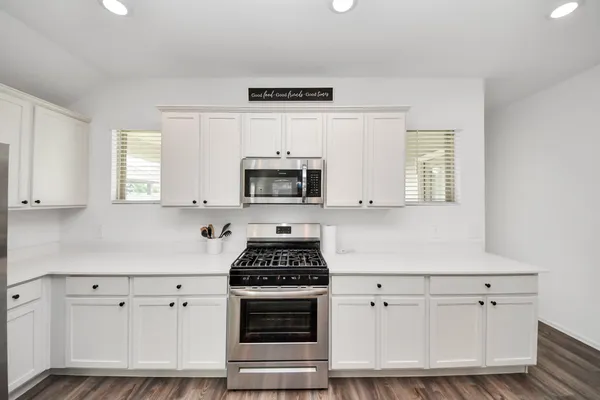 a kitchen with white cabinets white stainless steel appliances and sink