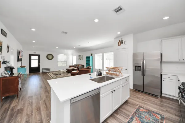 a kitchen with a sink a counter top space stainless steel appliances and wooden floor