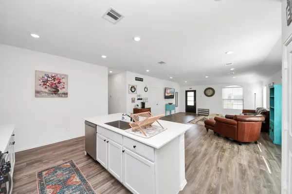 a large white kitchen with stainless steel appliances granite countertop a stove and a wooden floors