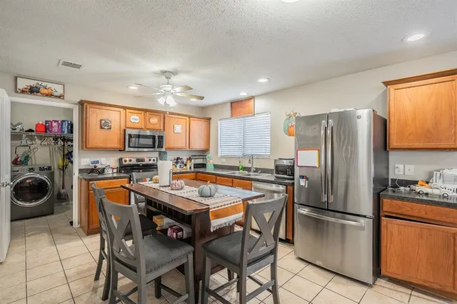 a kitchen with stainless steel appliances granite countertop a table chairs sink refrigerator and microwave