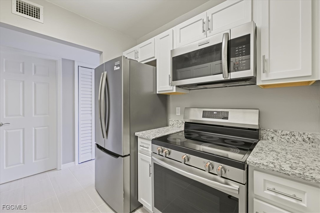 3225 East Riverside Drive, Unit 63F Fort Myers, FL 33905 - Photo 13 of 30 a kitchen with stainless steel appliances white cabinets and a stove top oven