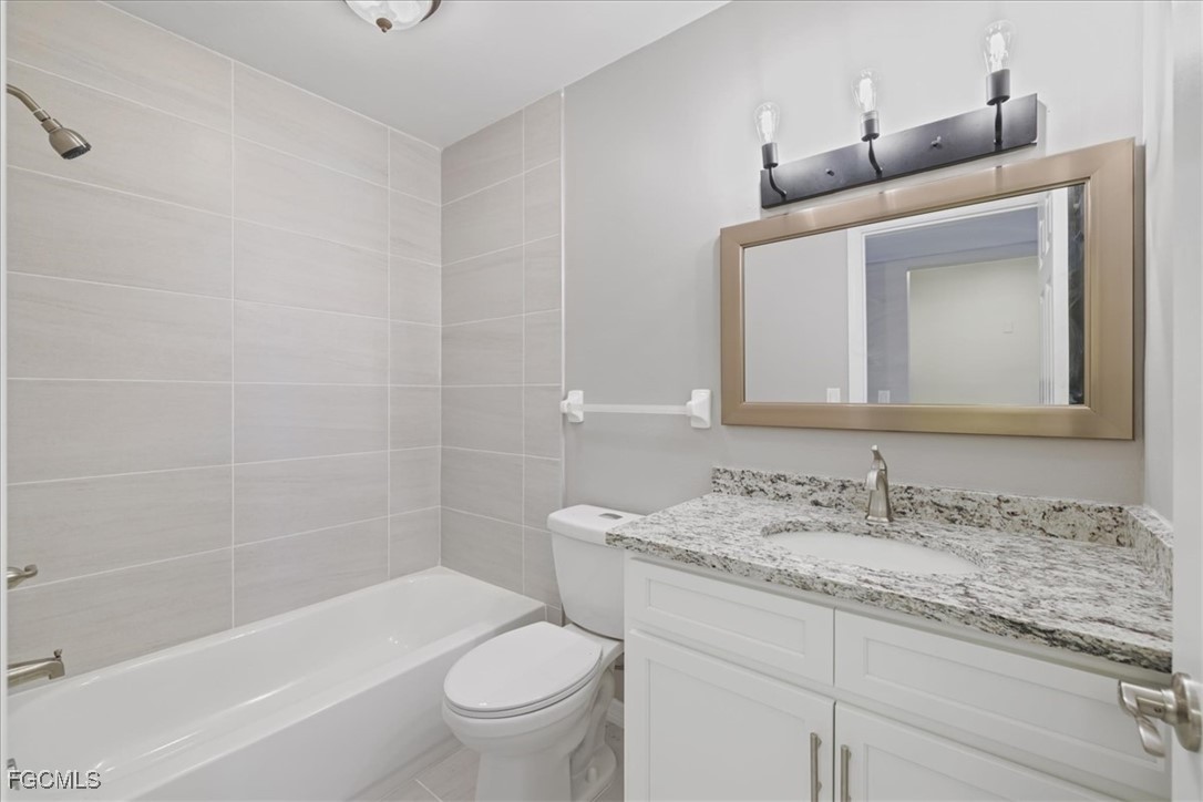 3225 East Riverside Drive, Unit 63F Fort Myers, FL 33905 - Photo 17 of 30 a bathroom with a granite countertop sink a toilet and bathtub