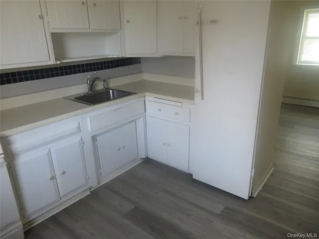 a kitchen with white cabinets and sink
