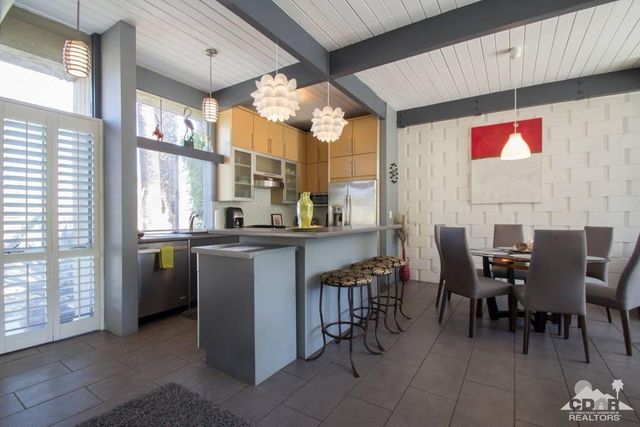 a very nice looking dining room with kitchen island granite countertop a table chairs sink and cabinets
