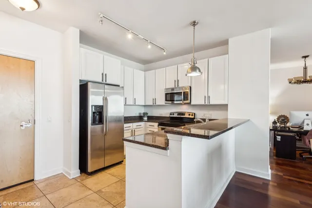 a kitchen with stainless steel appliances granite countertop a refrigerator stove and white cabinets