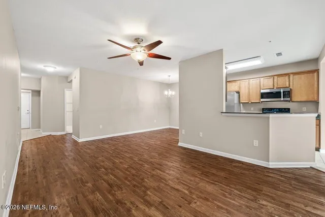an empty room with wooden floor fan and windows