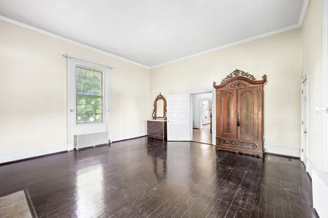 an empty room with wooden floor fireplace and windows