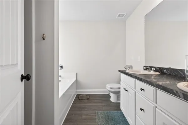 a bathroom with a granite countertop sink a toilet and a mirror