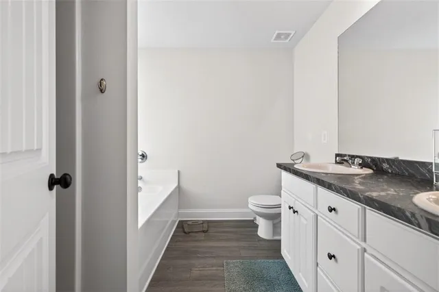 a bathroom with a granite countertop sink a toilet and a mirror