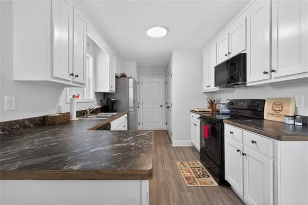 a kitchen with stainless steel appliances granite countertop a stove top oven a sink a refrigerator and white cabinets