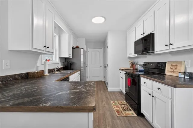 a kitchen with stainless steel appliances granite countertop a stove top oven a sink a refrigerator and white cabinets