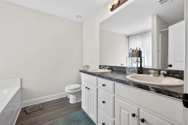 a bathroom with a granite countertop sink a toilet and a mirror