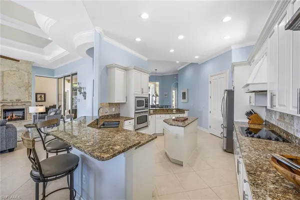 a large white kitchen with stainless steel appliances granite countertop a stove and a sink