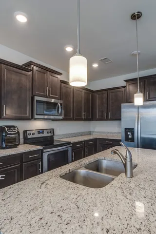a kitchen with stainless steel appliances granite countertop a sink a stove and a refrigerator