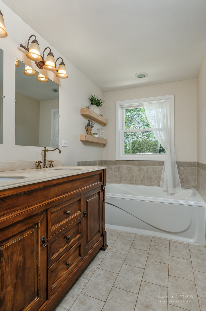 14725 Sears Road Plano, IL 60545 - Photo 14 of 26 a spacious bathroom with a granite countertop sink a large mirror and a bathtub