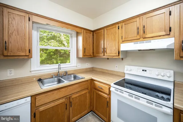 a view of a refrigerator in kitchen and an empty room
