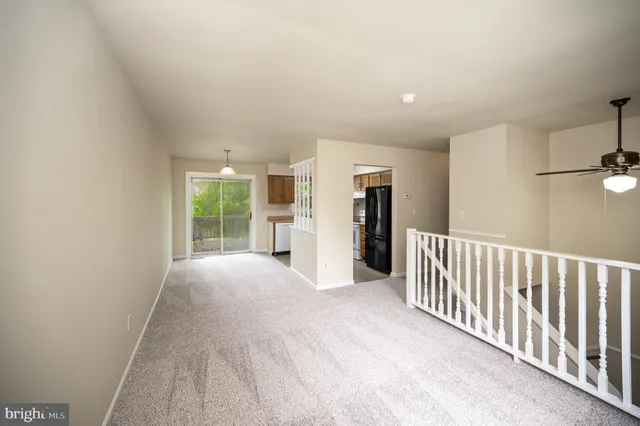 a view of an empty room with a window and kitchen view