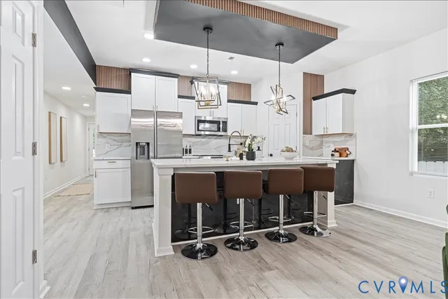 a kitchen with stainless steel appliances kitchen island granite countertop a sink cabinets and wooden floor