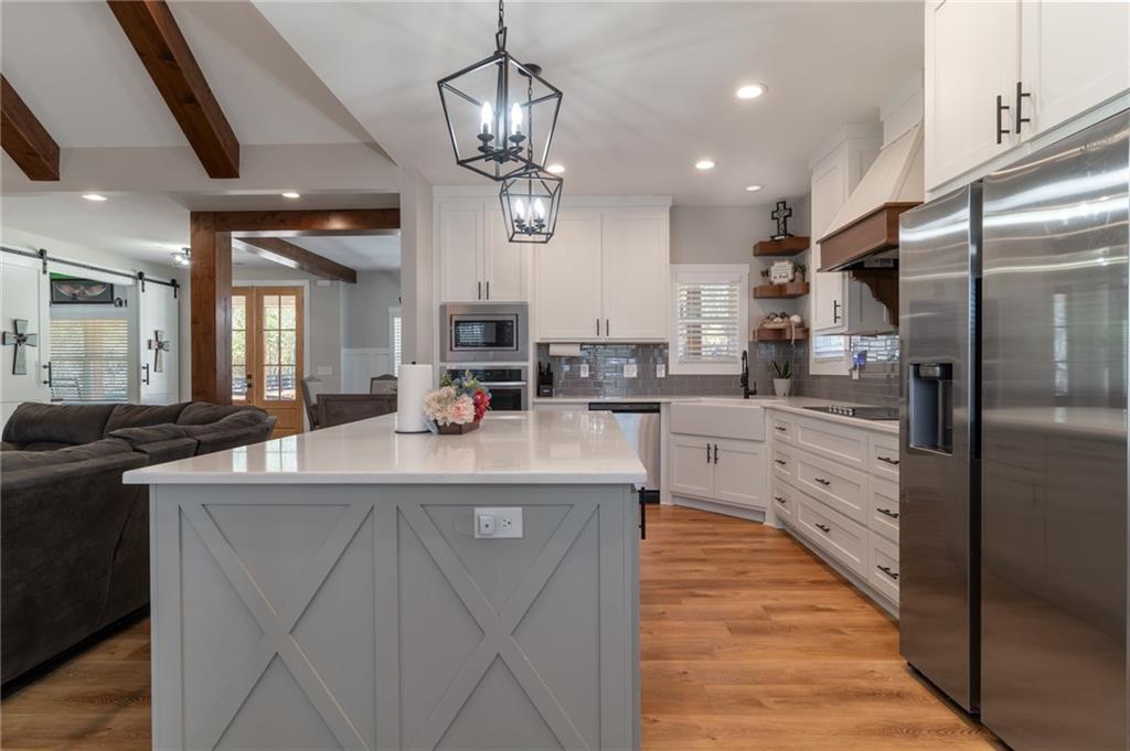 2250 Sperin Road Ball Ground, GA 30107 - Photo 11 of 56 a large kitchen with stainless steel appliances kitchen island granite countertop a refrigerator a stove a sink and a dining table with wooden floor