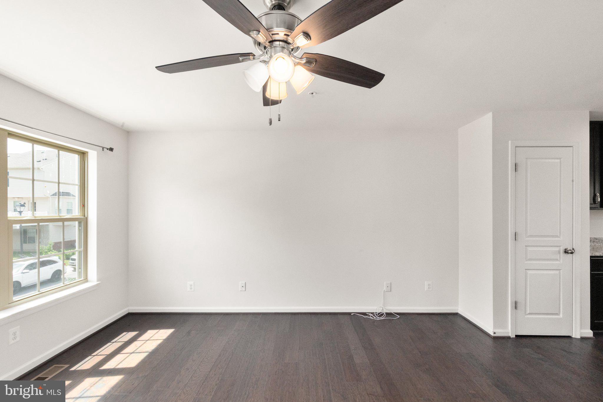 9943 Ravenhurst Road Middle River, MD 21220 - Photo 7 of 23 an empty room with wooden floor chandelier fan and windows