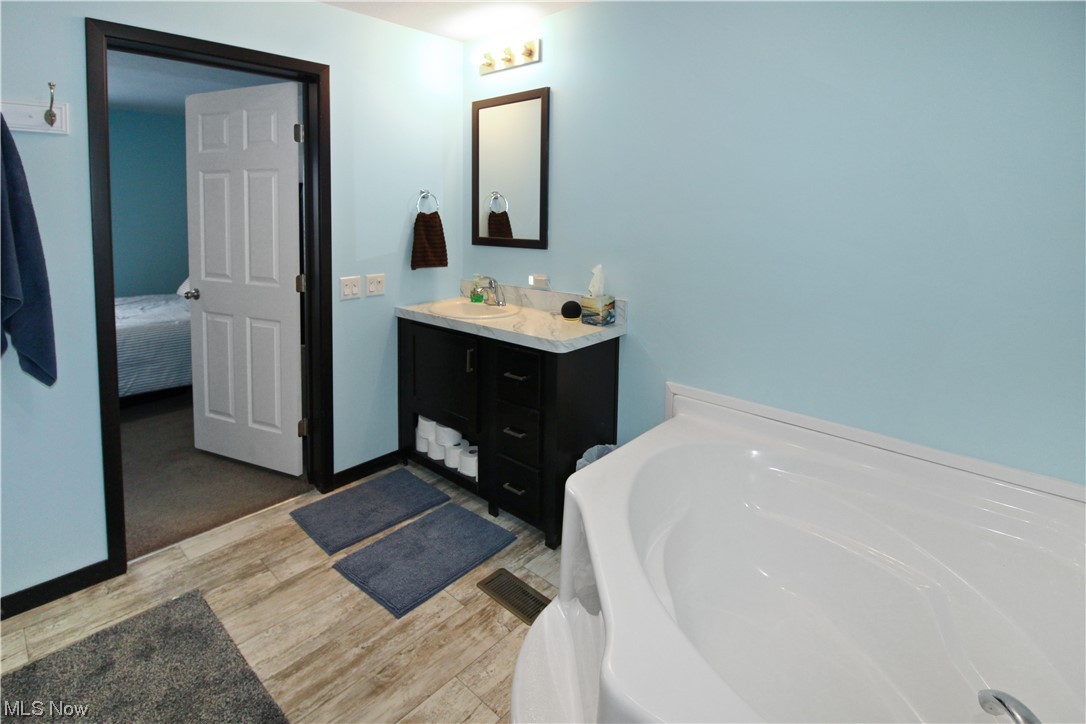 1609 Coldwater Crossing Road Lakeside Marblehead, OH 43440 - Photo 28 of 38 Bathroom featuring a bathtub, vanity with extensive cabinet space, and hardwood / wood-style floors