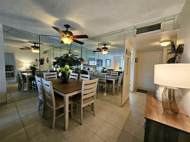 a dining room with stainless steel appliances kitchen island granite countertop a table chairs and a refrigerator