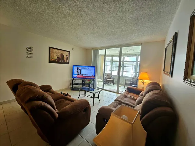 a living room with furniture a flat screen tv and a window