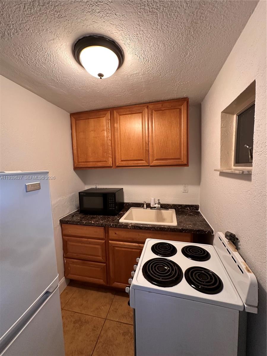 6131 Southwest 39th Street, Unit EAST Miramar, FL 33023 - Photo 14 of 15 a kitchen with a sink a stove and cabinets