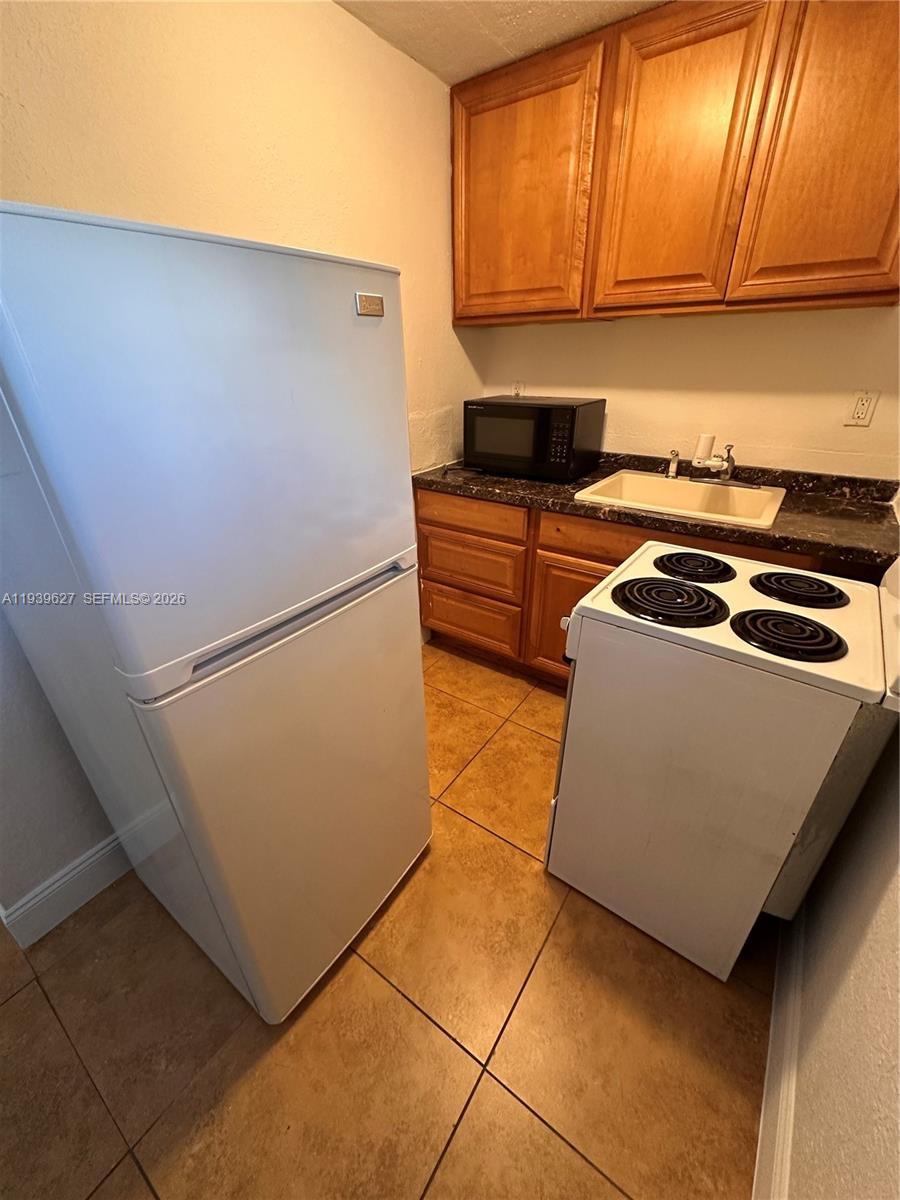 6131 Southwest 39th Street, Unit EAST Miramar, FL 33023 - Photo 4 of 15 a kitchen with granite countertop a refrigerator a stove a sink and dishwasher